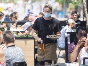 A server brings an order to a customer at a restaurant in Montreal, Sunday, June 6, 2021.