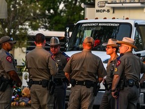 Police officers speak near a makeshift memorial for the shooting victims outside Robb Elementary School in Uvalde, Texas, on May 27, 2022.