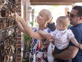 Brooke Spitse, who was diagnosed with breast cancer in January of this year, puts a lock on the healing garden wall while being joined by her family: husband, Trevor Spitse, and 9-month-old son, Tyson, during a Lock Out Cancer Campaign event outside the Windsor Regional Cancer Centre, on Sunday, May 29, 2022.