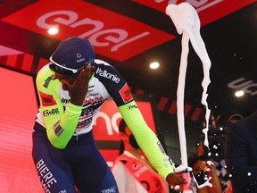 Eritrean rider Biniam Girmay Hailu reacts after popping a champagne cork as he celebrates on the podium after winning the 10th stage of the Giro d'Italia 2022 cycling race.