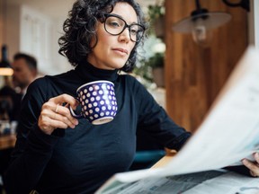 A woman reading a newspaper and having coffee. Getty Images