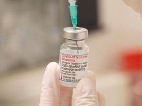 A health care worker fills up a syringe with a dose of Moderna's COVID-19 vaccine for a booster shot in Zurich, Switzerland, Nov. 17, 2021.