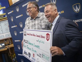 Unifor Local 444 President, David Cassidy, left, and Windsor Lancers men's hockey coach, Kevin Hamlin, hold up a cheque for $50,000 during a press event at the Capri Pizzeria Recreation Complex, on Tuesday, May 24, 2022.  The funds will go towards the men's hockey team traveling to British Columbia to assist indigenous communities recover from flooding and forest fires.