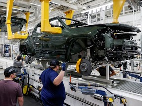 Employees works on an assembly line at startup Rivian Automotive's electric vehicle factory in Normal, Illinois, U.S. April 11, 2022.