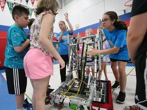 St. Gabriel Catholic Elementary School student Ella Foreman, left, and Carly Bastien (both facing camera) explain to younger students details of the robot they and other classmates programmed.