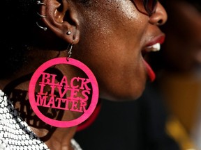 A Black Lives Matter protester wears custom earrings during a demonstration outside the office of Sacramento district attorney Anne Schubert, in Sacramento, Calif., March 28, 2018.