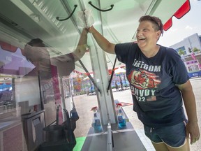 Happy days. Maggie Prince wipes down the windows to the Funnel Cake booth as workers set up for the start of the midway carnival along Windsor's riverfront until July 3.