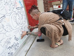 Forster Secondary School alumna Rebecca Entwistle signs the west-end school’s front door during a celebration of the school’s 100th anniversary on Saturday, June 11, 2022.