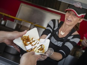 Robin Redcliffe, of Herbert's Fries, serves up a Prego Pleaser poutine to Evin Kolm at Poutinefest on Thursday, June 9, 2022.  Poutinefest is happening all weekend down at the Riverfront Festival Plaza.