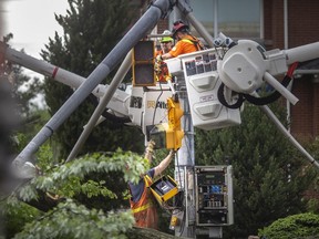 Utility crews work to repair a traffic light pole that was damaged after a tree fell onto it at the intersection of Ouellette Avenue and Ellis Road during a brief but powerful early-afternoon storm that moved through the area on Wednesday, June 1, 2022.
