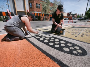 Arts and culture project creators from across Windsor are eligible for a new round of city grants. In this May 10, 2022, file photo, artist Julie Hall, right, assisted by Christina Sisti, work on a crosswalk art piece on Drouillard Road. The piece entitled Plant 1 adds to the many new art works in the Ford City area.