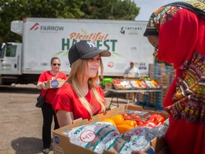 Addy Roberts, a 14-year-old volunteer with the new mobile food pantry started by Caesars Windsor Cares and HUB - Hub of Opportunities, hands out a hamper full of fresh produce to a community member in Windsor's west end on July 15, 2022.