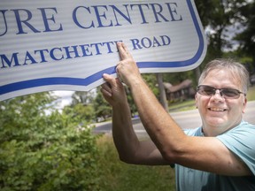 Al Matchett covers the 'e' on Matchette Road outside the Ojibway Nature Centre, on Tuesday, July 12, 2022.  Matchett's family has been campaigning for many years to convince the City of Windsor to correct the spelling of the road named after an 19th century ancestor. Removal the extra vowel was finally approved by city council Monday night.