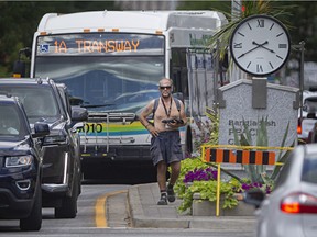As traffic flows by in both directions, a panhandler stands on a boulevard in the middle of Ouellette Avenue at Wyandotte Street in downtown Windsor on Tuesday, July 12, 2022.