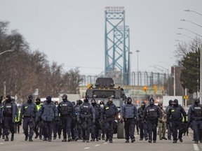 In this Feb. 13, 2022, photo, a large police force marches south on Huron Church Road, clearing away protesters.