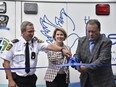 Chris Grant, deputy chief of planning and physical resources for Essex-Windsor EMS, Nancy Brockenshire, The Hospice executive director, and John Fairley, founder of the Face to Face campaign, cut the ribbon on Monday, Aug. 15, 2022, unveiling a repurposed ambulance that will be used by Hospice in a new program to provide social and quality-of-life visits to hospice patients and their families.