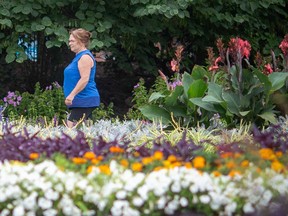 Flowers and plants surround a woman as she walks in Windsor's Jackson Park on Aug. 4, 2022.