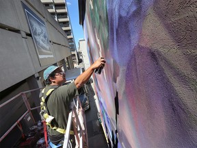 Mural artist Moises 'Luvs' Frank works on a piece in Windsor's Art Alley on Friday, August 12, 2022.