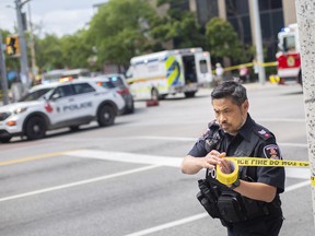 A Windsor police officer tapes off the intersection of Wyandotte Street and Ouellette Avenue after a man was shot by police after wielding a machete at people, on Monday, August 15, 2022.