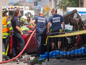 Windsor firefighters work to free a woman from the car she was driving while EMS paramedics provide care after she struck a building at the corner of Curry Avenue and Wyandotte Street West, on Thursday, August 25, 2022.