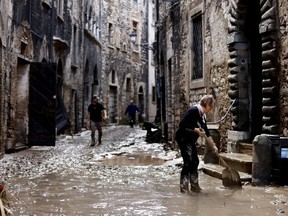 People work to clear the way after heavy rains and deadly floods hit the central Italian region of Marche, in Cantiano, Italy, Friday, Sept. 16, 2022.