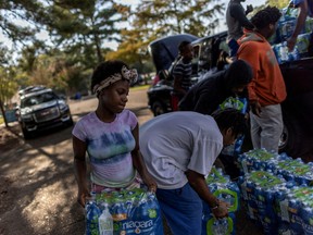 Volunteers carry bottles of water at a water distribution site as the city of Jackson goes without reliable drinking water last week.