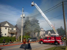 A firefighting unit deploys its aerial tower to deal with a house fire in the 1100 block of Walker Road in Windsor on Sept. 21, 2022.