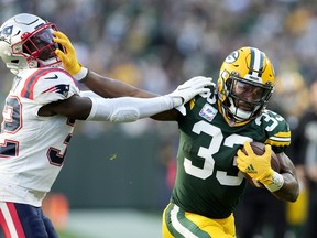Aaron Jones of the Green Bay Packers stiff arms Devin McCourty of the New England Patriots.