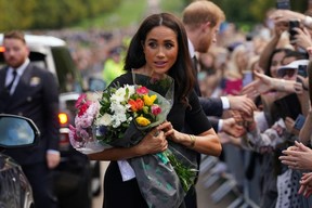 Meghan, Duchess of Sussex collects flowers as she chats with well-wishers on the Long walk at Windsor Castle on September 10, 2022, two days after the death of Britain's Queen Elizabeth II at the age of 96. (Photo by KIRSTY O'CONNOR/POOL/AFP via Getty Images)