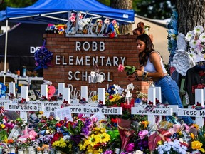 A girl lays flowers at a makeshift memorial at Robb Elementary School in Uvalde, Texas after a gunman killed 21 people inside the school, May 28, 2022.
