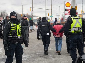 Police officers make an arrest after clearing the blockade of the Ambassador Bridge by Freedom Convoy supporters in Windsor on Feb. 13, 2022.