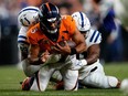 Oct 6, 2022; Denver, Colorado, USA; Denver Broncos quarterback Russell Wilson (3) is tackled by Indianapolis Colts defensive tackle DeForest Buckner (99) and defensive end Yannick Ngakoue (91) in the third quarter at Empower Field at Mile High.