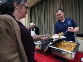 Jason Weinberg, executive director of the Windsor Residence for Young Men serves Louise Bacon at a charity pasta night event at the Caboto Club on Wednesday, October 5, 2022.