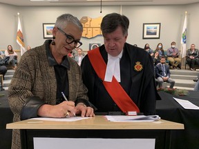 Justice George W. King watches Wednesday night as Leamington Mayor Hilda MacDonald signs a statement officially making her the first principal in Essex County history.