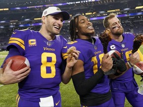 Vikings' Kirk Cousins, left, Justin Jefferson, centre, and Adam Thielen, right, eat turkey legs on the field after defeating the Patriots at U.S. Bank Stadium in Minneapolis, Thursday, Nov. 24, 2022.