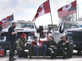 Anti-mandate protestors sit on a sofa at the intersection of College and Huron Church near the Ambassador Bridge in Windsor on Wednesday, February 9, 2022.