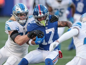 New York Giants wide receiver Wan'Dale Robinson breaks a tackle by Detroit Lions linebacker Alex Anzalone in front of cornerback Mike Hughes during the second half at MetLife Stadium.