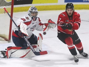 Windsor Spitfires' goalie Mathias Onuska and Owen Sound Attack forward Deni Goure eye a bouncing puck during Wednesday's game at the WFCU Centre.