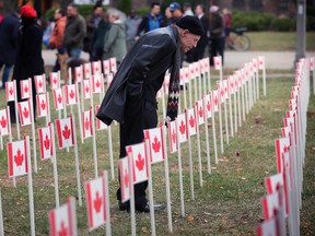 Glen Teskey reads names of fallen veterans on flags at the City of Windsor's Remembrance Day ceremony at the downtown cenotaph on Friday, Nov. 11, 2022.