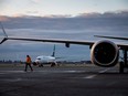 A ground worker walks under one of the wings of a WestJet Airlines Boeing 737 Max aircraft after it arrived at Vancouver International Airport, in Richmond, B.C., Thursday, Jan. 21, 2021.