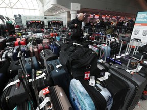 A man searches through baggage and luggage destined for Aruba in roped off section of Pearson International airport’s Terminal 3. A perfect storm of weather broken down luggage conveyors and packed airports have resulted in ongoing chaos for travellers. on Tuesday December 27, 2022.