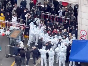 Residents confront workers donned in protective suits who are blocking the entrance of a residential compound in Shanghai, China, in this still image obtained from a social media video released November 30, 2022.