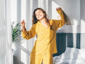 Woman in yellow pyjamas dancing in the morning in bedroom.