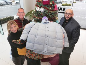 Tina Gatt, manager, community outreach and Mike Clark, manager of public relations and fund development at the Windsor-Essex Children's Aid Society poses with Mustapha Abdulhamid, general manager at Rafih Auto Group's Jaguar Land Rover dealership on Thursday, December 22, 2022. The Rafih Auto Group collected a substantial number of coats, hats and gloves for the organization.