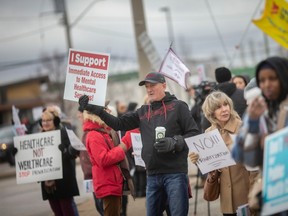 Dozens of protesters rally for better health care at the intersection of Walker Road and Tecumseh Road East, on Monday, Dec. 12, 2022.