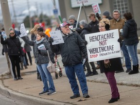 Dozens of protesters rally for better health care at the intersection of Walker Road and Tecumseh Road East, on Monday, Dec. 12, 2022.