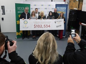Jeff Burrows, drummer for the S'Aints band, left, Brenda LeClair, Chatham Outreach for Hunger, Ron Seguin, St. Clair College, June Muir, Unemployed Help Centre, Patti France, St. Clair College, Tim Trombley and Mary Riley, Caesars Windsor pose with a ceremonial cheque at a press conference on Thursday December 22, 2022 at the Unemployed Help Centre in Windsor.