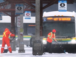 Workers clear areas around Transit Windsor buses at the downtown station on a snowy Friday, December 23, 2022.