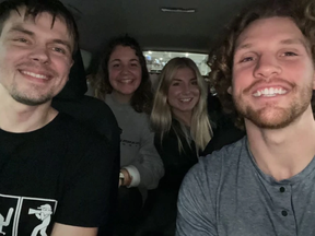 Four people, two men, two women, posing for selfie in car.