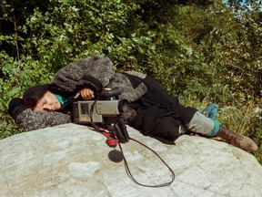 This image by John Kennedy shows renowned Indigenous filmmaker Alanis Obomsawin resting on a rock beside the Lake of Two Mountains in 1990. Obomsawin is one of dozens of artists with works featured in the Media City Film Festival’s ThousandSuns Cinema: Indigenous Edition.